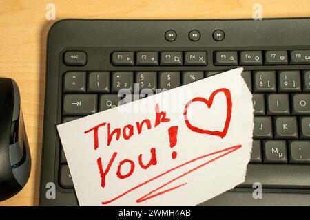 Messaggio di ringraziamento scritto a mano in rosso sulla tastiera del computer. Foto Stock