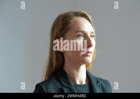 Ritratto di profilo di una giovane donna adulta attraente con un abito nero su sfondo bianco con un'espressione severa sul viso. Foto Stock