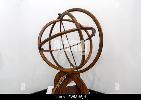 Antica sfera armillare in ottone su un piedistallo in legno su sfondo bianco. l'antico schema del movimento delle stelle celesti Foto Stock