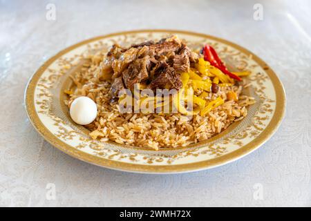 concetto di cucina orientale. Pilaf uzbeko fatto in casa o plov di agnello nel piatto. Foto Stock