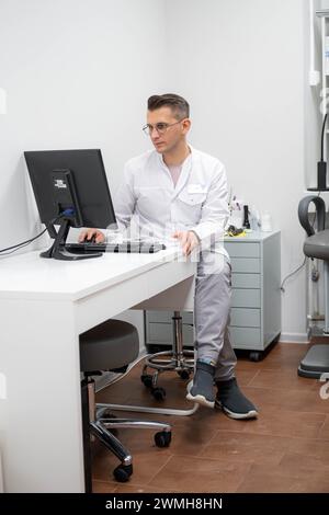 medico in oculistica, optometrista professionista sul lavoro: specialista oculistico in un ufficio clinico con sedia per esami e macchine diagnostiche pronte Foto Stock