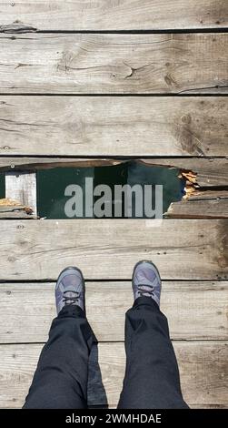 Un uomo cammina su un ponte di legno, un ponte di legno rotto Foto Stock