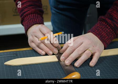 Primo piano delle mani di un uomo che misura un pezzo di pelle con una matita e un righello Foto Stock
