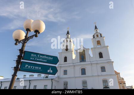 Minsk, Bielorussia - 7 gennaio 2024: Cartelli stradali e la cattedrale di Minsk dello Spirito Santo sullo sfondo. Il testo significa Piazza della città della libertà e città h Foto Stock