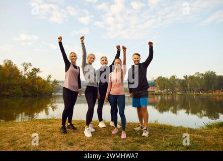 Persone felici e soddisfatte in piedi sulla riva del lago dopo gli esercizi sportivi nel parco. Foto Stock