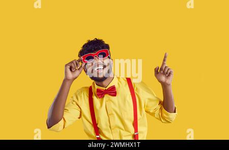 Felice giovane indiano in divertente vestito da festa ballando isolato su sfondo di colore giallo Foto Stock