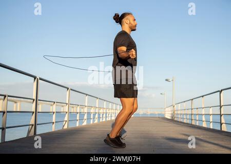L'uomo sportivo si impegna in acrobazie saltando con la corda all'aperto Foto Stock