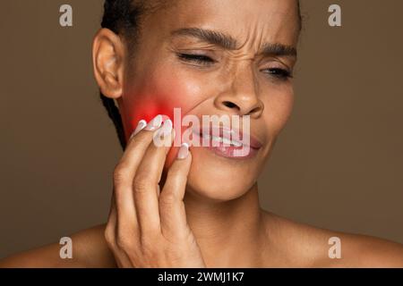 Donna afroamericana con macchia rossa sulla guancia che indica dolore Foto Stock
