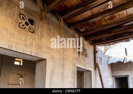 Edificio residenziale in rovina con ornamenti di fiori arabi scolpiti e tradizionale tetto in paglia fatto di rami di palma a Jazirah al Hamra, Emirati Arabi Uniti Foto Stock