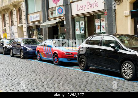 Figueres, Spagna - 14 maggio 2023: Una vivace auto rossa e blu, decorata con il logo del FC Barcelona e i temi di design, è parcheggiata dal marciapiede su un urba Foto Stock