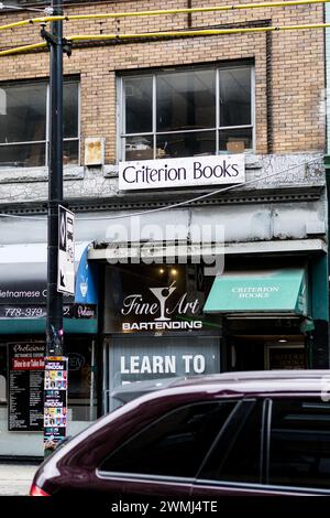 Una foto di una libreria, una scuola di bartending e un ristorante vietnamita dall'altra parte della strada su Pender Street, con un'auto in primo piano. Foto Stock