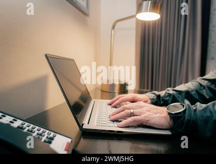primo piano delle mani di un uomo che digita su un computer presso una scrivania dell'ufficio Foto Stock