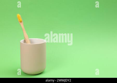 Spazzolino da denti in bambù nel supporto su sfondo verde, spazio per il testo Foto Stock