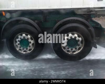 Le ruote del camion spruzzano acqua su strada. Pericoli durante la guida in prossimità di autocarri Foto Stock