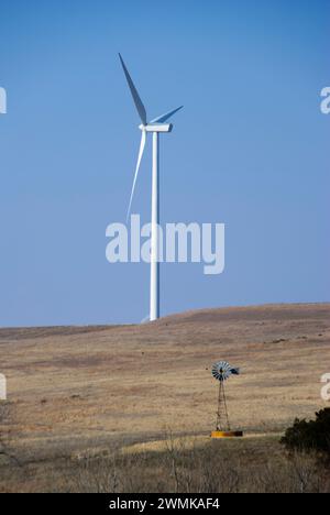 Progresso nell'energia eolica, una nuova turbina eolica sorge torreggiante accanto a un vecchio mulino a vento Foto Stock