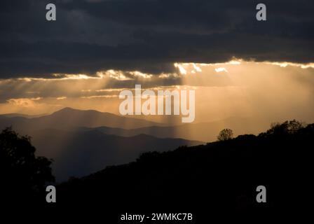 La luce del sole scorre attraverso le rotture nelle nuvole scure sulle Blue Ridge Mountains al tramonto; North Carolina, Stati Uniti d'America Foto Stock