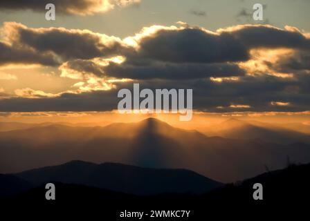 La luce del sole scorre da dietro le nuvole grigie per illuminare il monte Pisgah e Cold Mountain nelle Blue Ridge Mountains al tramonto Foto Stock