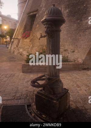 Fontana pubblica in ghisa con la testa di un leone al crepuscolo; Grottazzolina, regione Marche, Italia Foto Stock