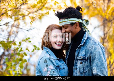 Primo piano di una coppia di corse miste che abbraccia, trascorrendo del tempo insieme durante una gita in famiglia autunnale in un parco cittadino: Edmonton, Alberta, Canada Foto Stock