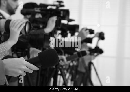 Giornalisti professionisti con microfoni e fotocamere al chiuso, primo piano. Effetto bianco e nero Foto Stock