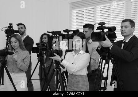 Giornalisti professionisti con telecamere al chiuso. Effetto bianco e nero Foto Stock