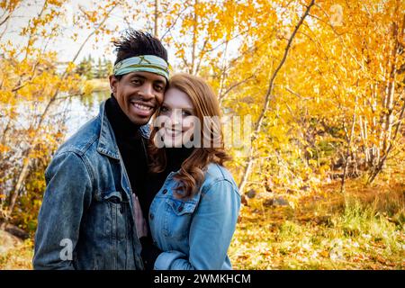 Ritratto ravvicinato di una coppia di sposi in gara mista che sorride alla telecamera, trascorrendo del tempo insieme durante un'uscita di famiglia autunnale... Foto Stock