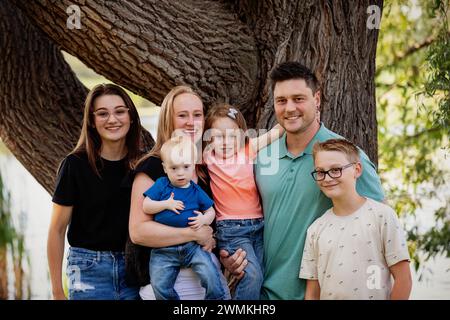 Ritratto di famiglia all'aperto in un parco cittadino in un caldo pomeriggio autunnale e il figlio più giovane ha la sindrome di Down; Leduc, Alberta, Canada Foto Stock