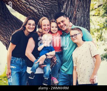 Ritratto di famiglia all'aperto in un parco cittadino in un caldo pomeriggio autunnale e il figlio più giovane ha la sindrome di Down; Leduc, Alberta, Canada Foto Stock