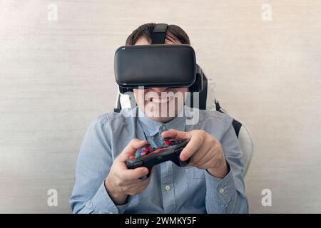 Giovane uomo che prova la realtà virtuale a casa, usando occhiali VR con visore e tenendo il joystick, gioca ai videogame. Tecnologie moderne ed entertè domestica Foto Stock