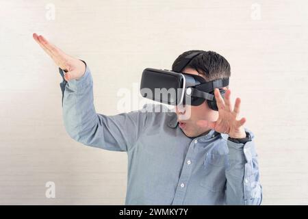 Un uomo felice negli occhiali VR sta urlando. Concetto di emozioni umane, espressione facciale, gadget e tecnologie moderne. La cuffia maschile in 3D sta ballando sulla w Foto Stock