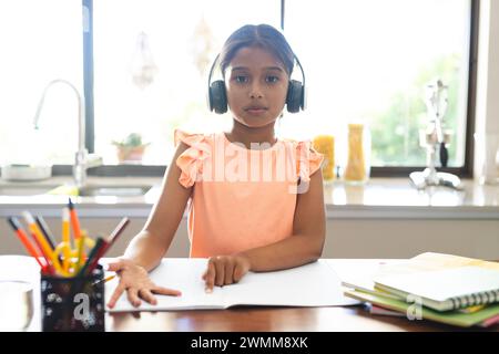 Ragazza birazziale studia a casa con una videochiamata, impegnata nell'apprendimento online Foto Stock