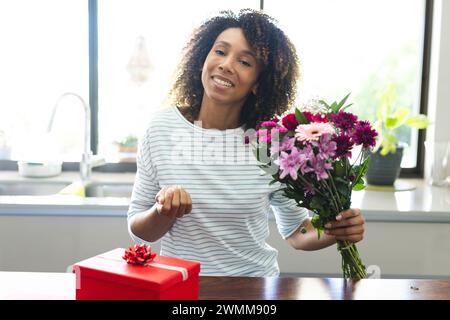 Una donna birazziale gode di un bouquet a casa durante una videochiamata online con spazio di copia Foto Stock
