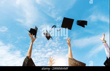 Laureati che lanciano cappelli graduati in aria Foto Stock