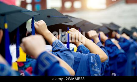 Il retro dei laureati mette le mani in alto di fila durante l'inizio Foto Stock