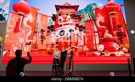 Besucherinnen vor Grossdisplay, Messestand China Mobile, MWC Mobile World Congress 2024, Barcellona, Spanien *** visitatori di fronte al grande display, China Mobile stand, MWC Mobile World Congress 2024, Barcellona, Spagna Foto Stock