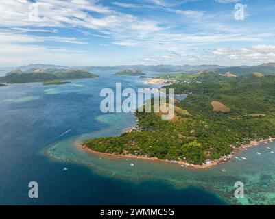 Paesaggio tropicale con barche in acque cristalline e isola con case. Coron, Palawan. Filippine. Foto Stock