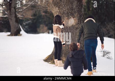 Una famiglia felice di tre persone che camminano sulla neve Foto Stock