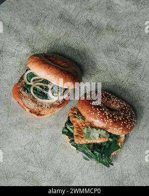 Angolo alto di un hamburger di due bagel con pollo, formaggio, insalata e verde Foto Stock