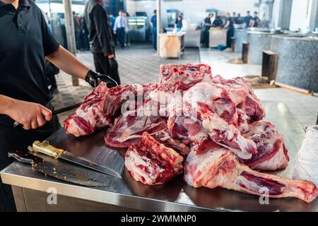 Un uomo che cucina taglia la carne con un coltello in un ristorante. macellazione di grandi pezzi di carne fresca in primo piano Foto Stock