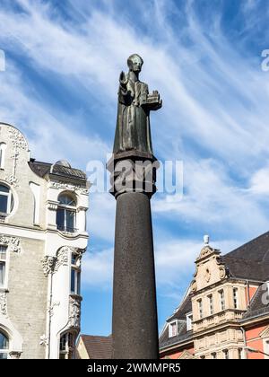 Essen, Germania - 21 agosto 2022: Scultura in bronzo del fondatore della città di Essen St. Ludgerus con un modello della chiesa di Ludgerus a Essen-Werden, NRW, GE Foto Stock