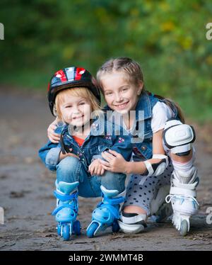 Due bambine rollerskating nel parco all'aperto Foto Stock