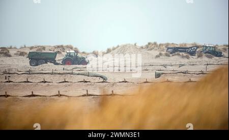 Rostock, Germania. 27 febbraio 2024. Sulla spiaggia di Warnemünde, i trattori raccolgono sabbia dalla zona del molo occidentale e poi la riportano a ovest. Ogni anno, il vento soffia diverse tonnellate di sabbia sulla spiaggia della località balneare del Baltico. Le tempeste di inizio gennaio in particolare hanno contribuito a questo. Crediti: Frank Hormann/dpa/Alamy Live News Foto Stock