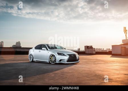 Lexus È UNA berlina parcheggiata al piano superiore del garage. Skyline della città sullo sfondo Foto Stock