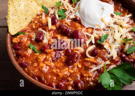 Peperoncino con carne con condimenti di formaggio e nachos da vicino. Cibo messicano fatto in casa, peperoncino con fagioli rossi e manzo macinato. Fagioli cileni. Foto Stock