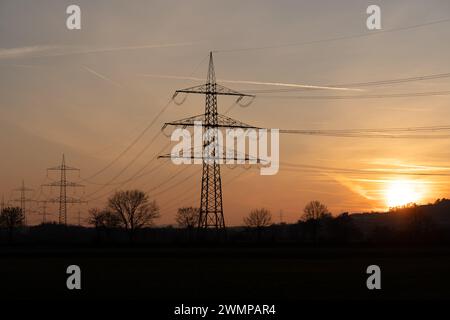 Le linee elettriche sagomate nella zona rurale al tramonto a Giessen, Germania Foto Stock