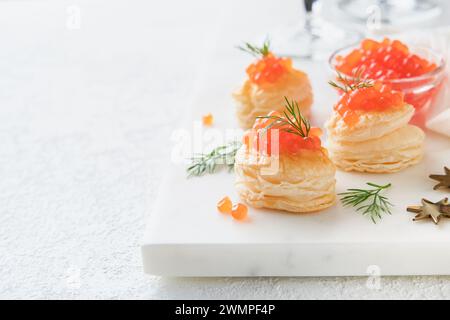 Toast al caviale rosso salmone. Canape natalizia o brindisi con caviale rosso su piatto bianco su sfondo chiaro. Un'idea per uno spuntino di Natale. Cibo da buongustai. Struttura di circa Foto Stock