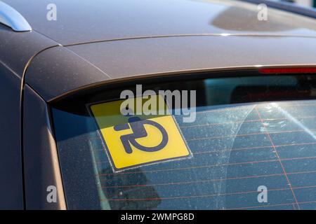Primo piano su un cartello giallo "conducente disabile" bloccato sul finestrino posteriore di un'auto. Foto Stock