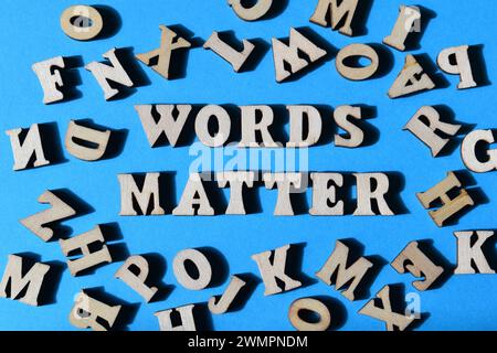 Le parole contano, frase in lettere dell'alfabeto di legno circondata da lettere casuali su sfondo blu Foto Stock