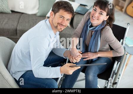 uomo e fidanzata in sedia a rotelle con un tablet Foto Stock