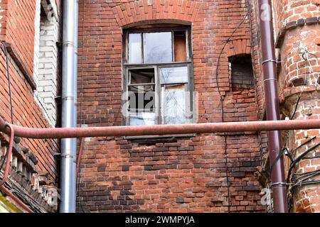 L'immagine mostra una parte di un vecchio muro di pietra con vetro rotto e un telaio della finestra rotto. Foto Stock